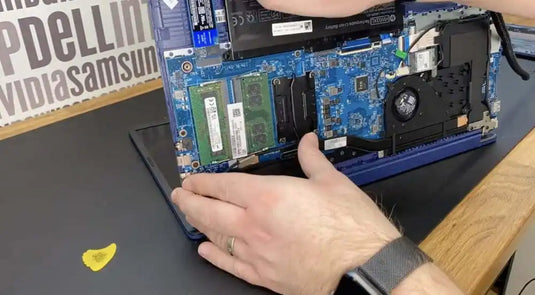 Blue laptop with open lid and exposed internal components, including ram sticks.